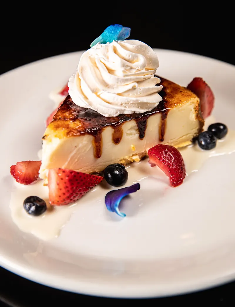 Crème brûlée cheesecake with whipped cream and fresh berries