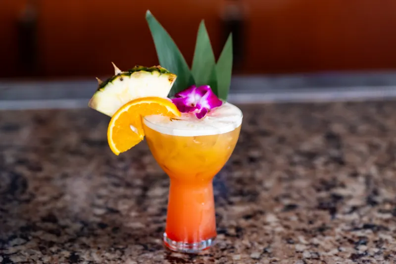 A Tropical Paradise cocktail with pineapple, orange and an orchid